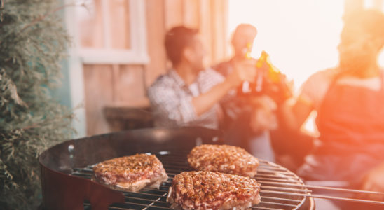 Bøffer på en grill med folk i baggrunden