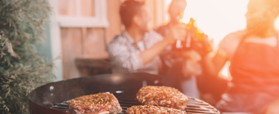 Bøffer på en grill med folk i baggrunden